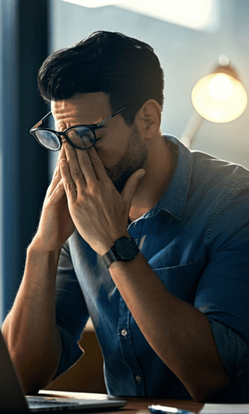 Man tired rubbing eyes, experiencing alert fatigue.